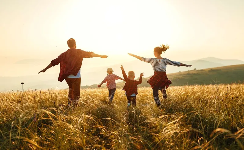 Family in fields running with arms up